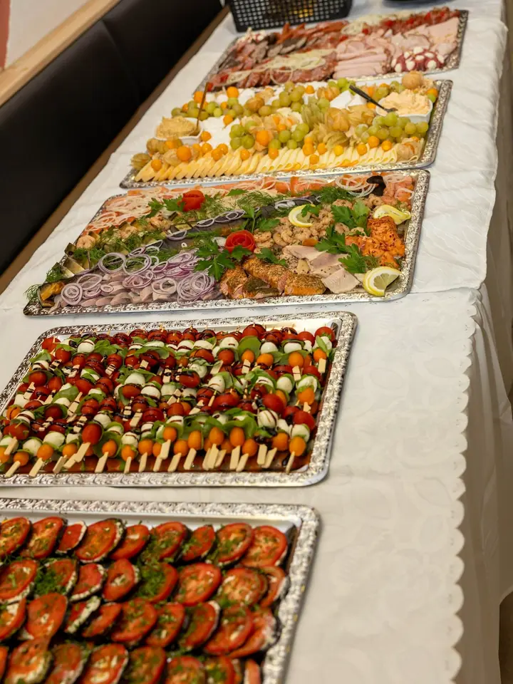 Lange Buffet-Tafel mit Fisch-, Wurst-, Spieß- und Tomatenplatten auf Silbertabletts