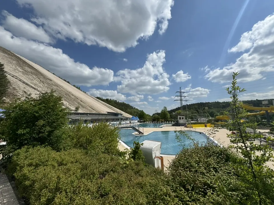 Blick über das Freibad auf den weißen Sandberg Monte Kaolino