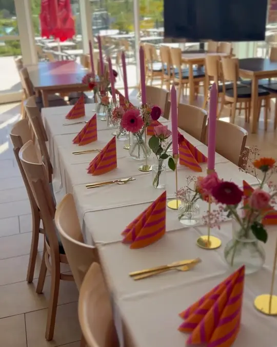 Festlich gedeckte Tafel mit Blumen und Kerzen im Gastraum