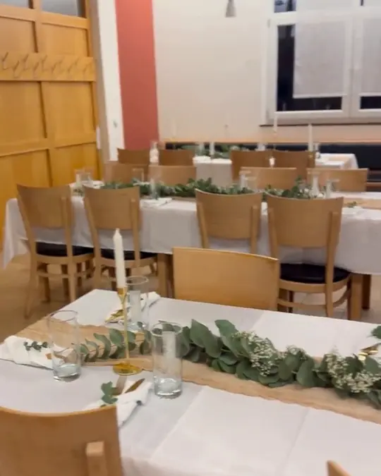Lange weiße Festtafel mit Eukalyptus und Kerzen im Gastraum